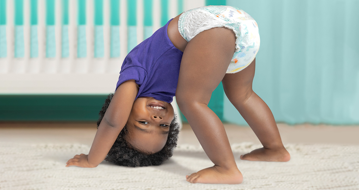A baby shows off his leak-free Pampers® Cruisers 360°™ pants, while cheerfully playing.