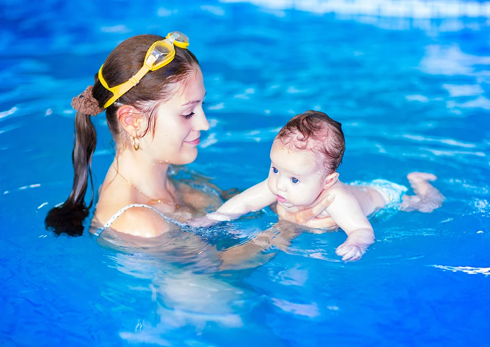 Bebê usando fraldas para nadar com a mamãe na piscina