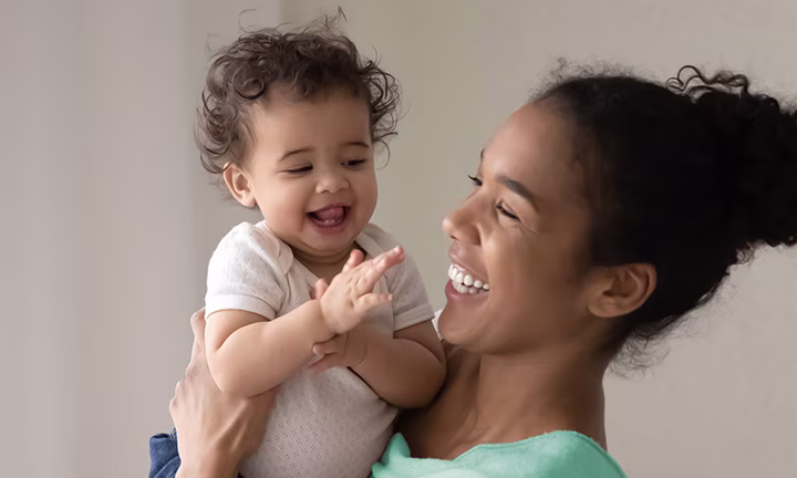 Smiling mother holding and laughing with her happy baby.