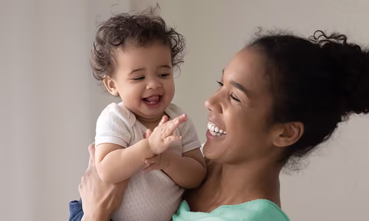 Smiling mother holding and laughing with her happy baby.