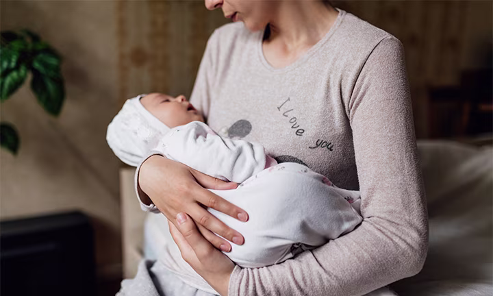 Mutter hält schlafendes Baby liebevoll auf dem Arm