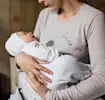 Mutter hält schlafendes Baby liebevoll auf dem Arm