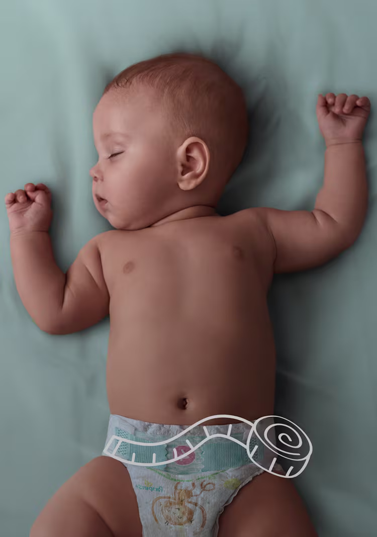 Baby sover på sängen, med en linjal över blöjans midjeband.