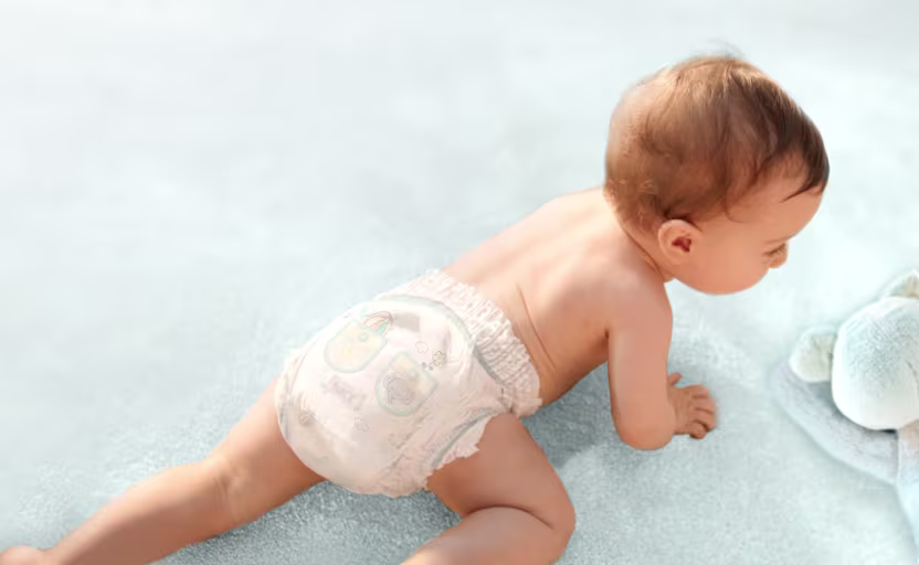 Ein glückliches Baby mit blauen Augen, das auf dem Bauch liegt und lächelt, während es nach oben und zur Seite schaut.