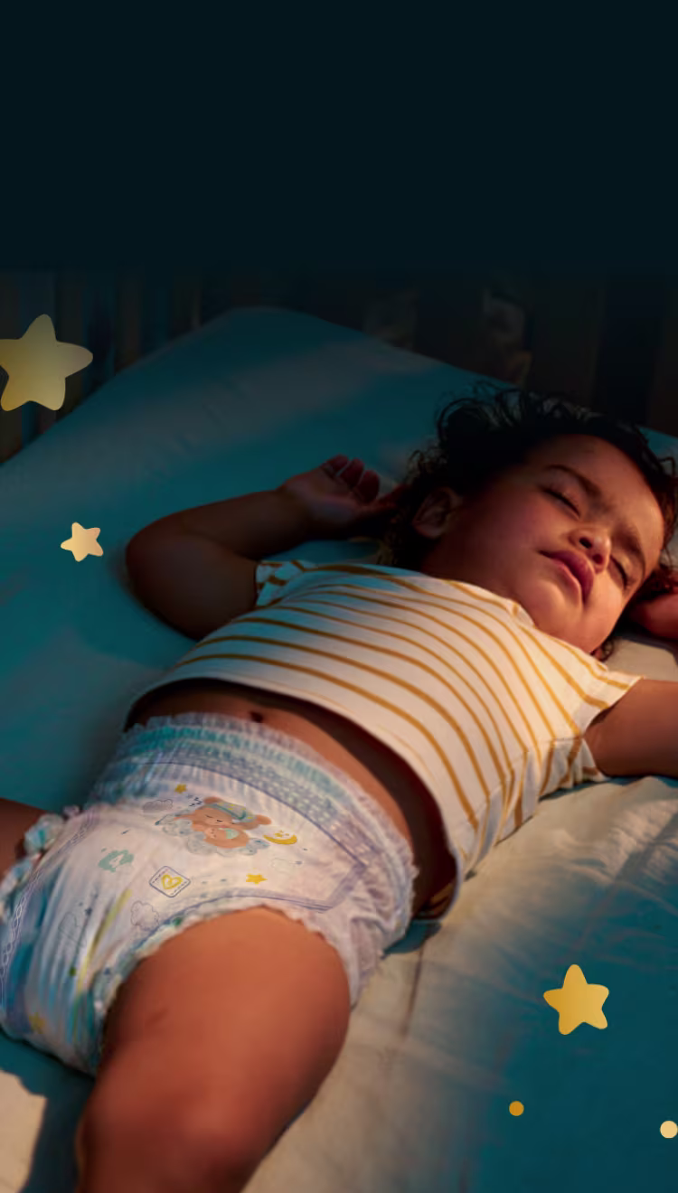 Ein Baby schläft friedlich auf dem Rücken und trägt eine Pampers® Night Pants mit Nachtdesigns.