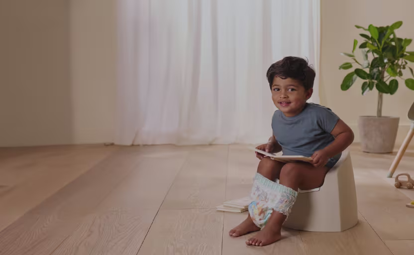 Pikkulapset, jotka istuvat potalla ja joilla on Pampers-housut jalassaan