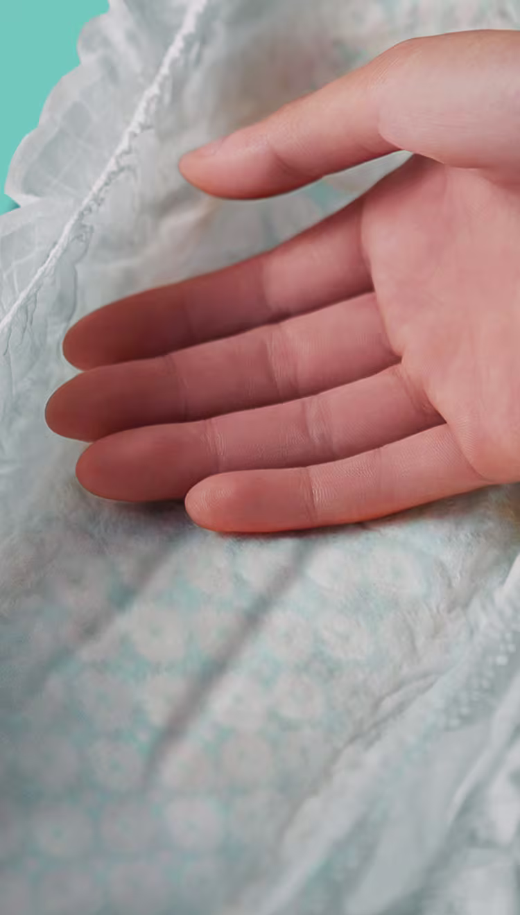 Ultra Suave. Mão tocando a fralda macia