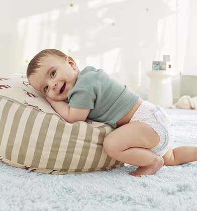 A baby wearing a nappy pant is on its hands and knees