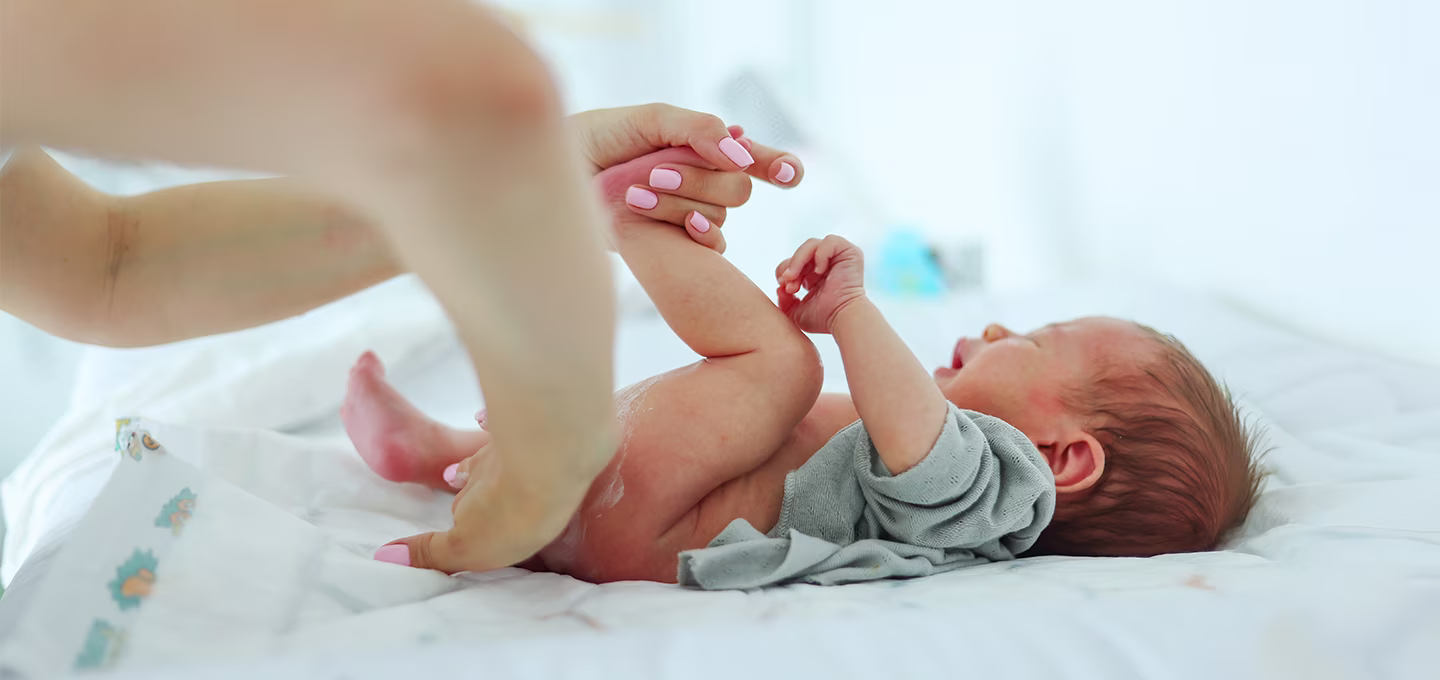 Ein Elternteil wechselt behutsam die Windel seines Babys – so kann mit sanfter Pflege Windeldermatitis gelindert werden.
