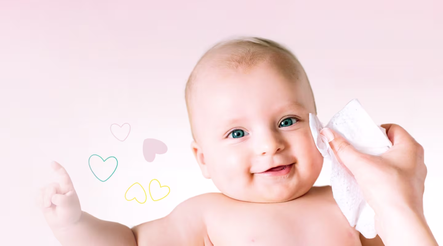 Zbliżenie na twarz dziecka, gdy ręka delikatnie wyciera jego policzek chusteczką Pampers Sensitive.