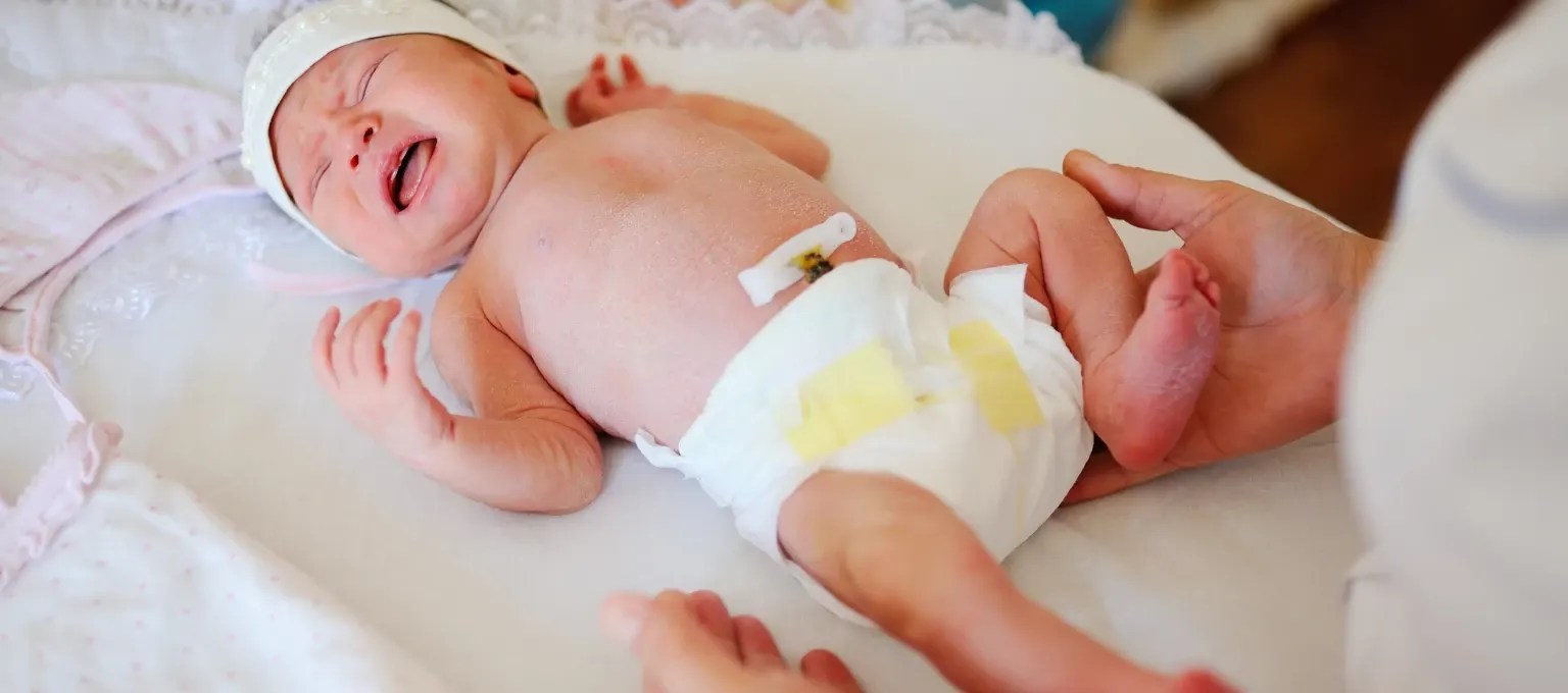 Mamá cambiando pañal a bebé con cordón umbilical