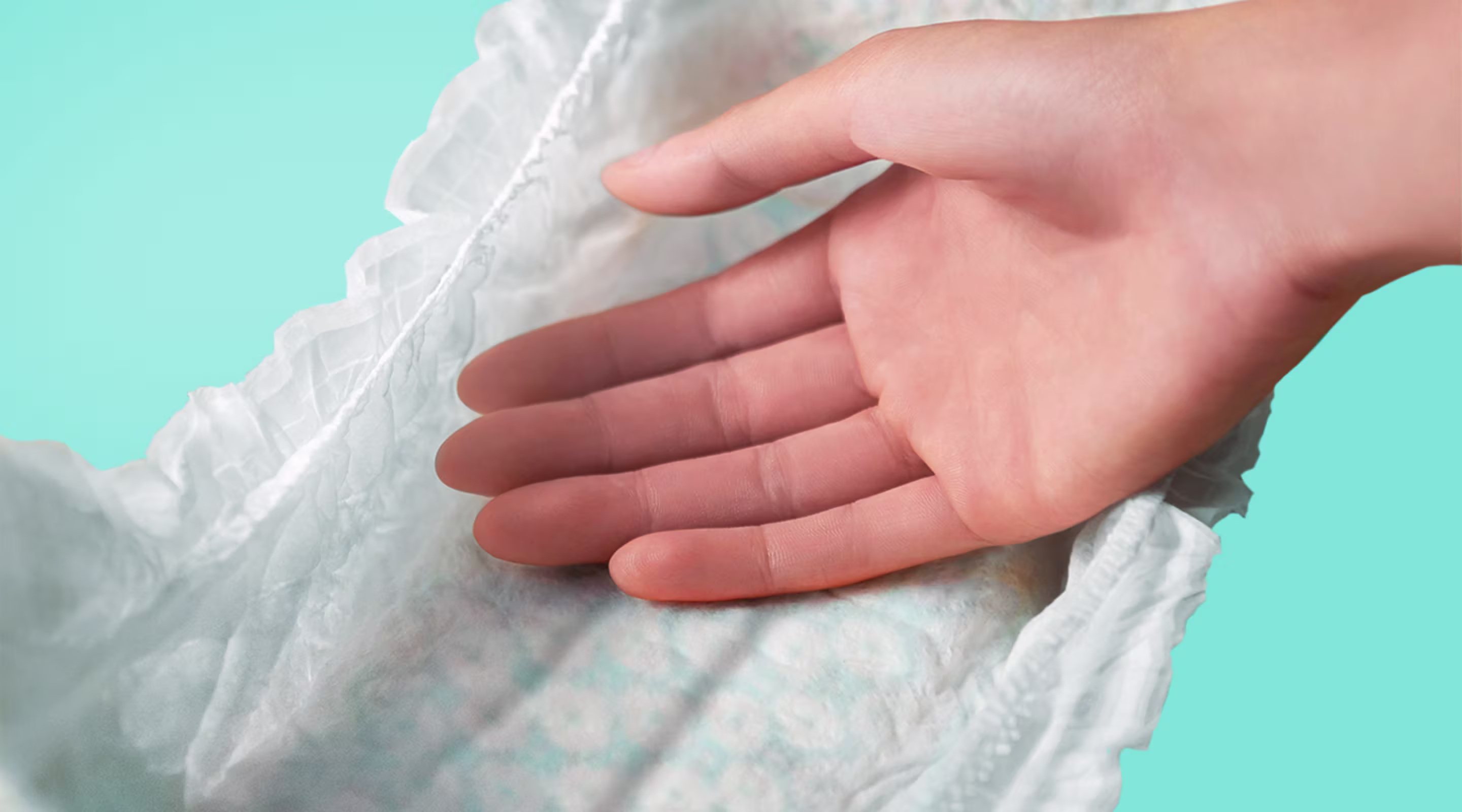 Ultra Suave. Mão tocando a fralda macia