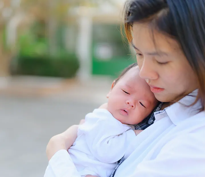 Parenting Myths Busted! Can You Spot Fact vs. Fiction? Mother gently cradling her sleeping baby outdoors.