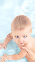 En baby ligger på rygg medan en person torkar babyns rumpa med en våtservett.