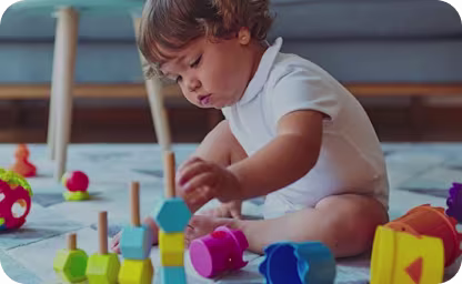 Baby playing with coloured toys on floor