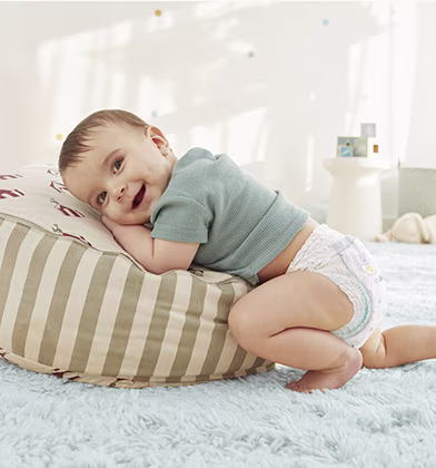 Dziecko w pieluszce klęczy, opierając się na rękach i kolanach