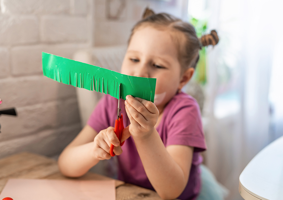 Niña recortando papel. Manualidades para niños