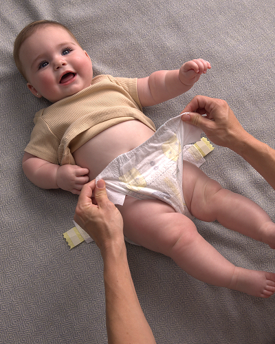 Parent gently securing a fresh diaper with the tapes, ensuring comfort and care.