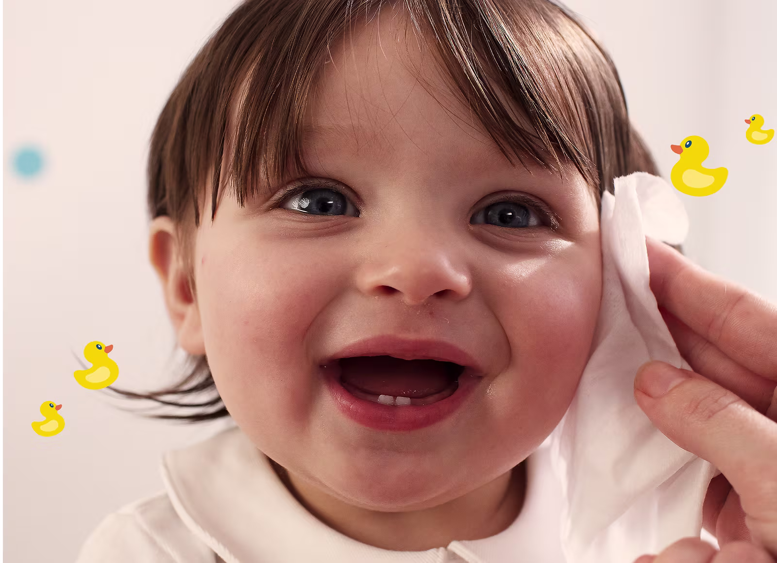 Eine Nahaufnahme des Gesichts eines Babys, während eine Hand sanft die Wange mit einem Pampers Fresh & Clean Feuchttuch reinigt.