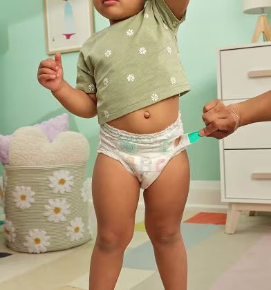 La mano de un padre retirando las pestañas EZ off de un pañal Pampers Cruisers 360 tipo pull on