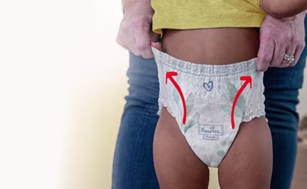 Foto de una mamá poniéndole el pañal calzón Pampers Pants a su bebé.