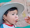Niño peruano comiendo receta saludable de Perú