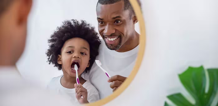 Criança escovando os dentes com o pai
