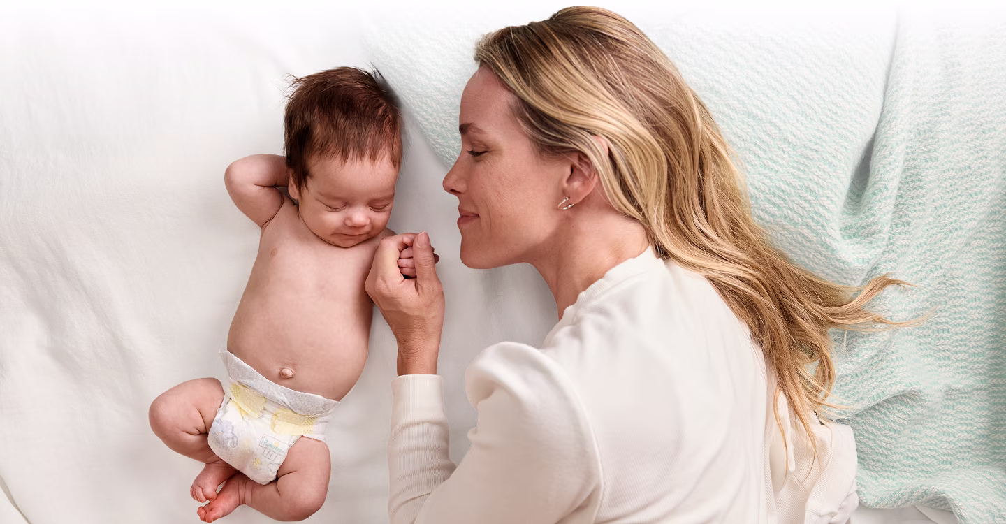 Mama oraz dziecko w pieluszce Pampers leżą obok siebie