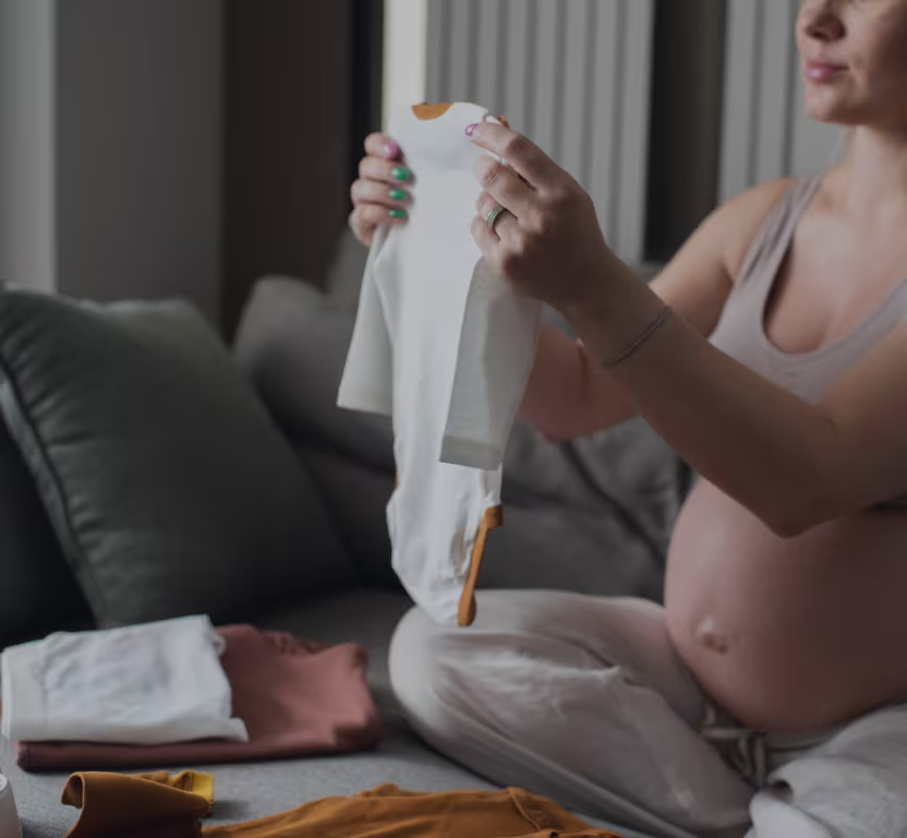A pregnant mum is seen folding baby clothes