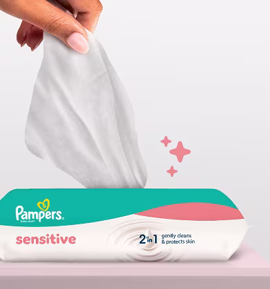 Nahaufnahme zeigt, wie eine Hand ein Pampers Sensitive Feuchttuch aus der Packung zieht.