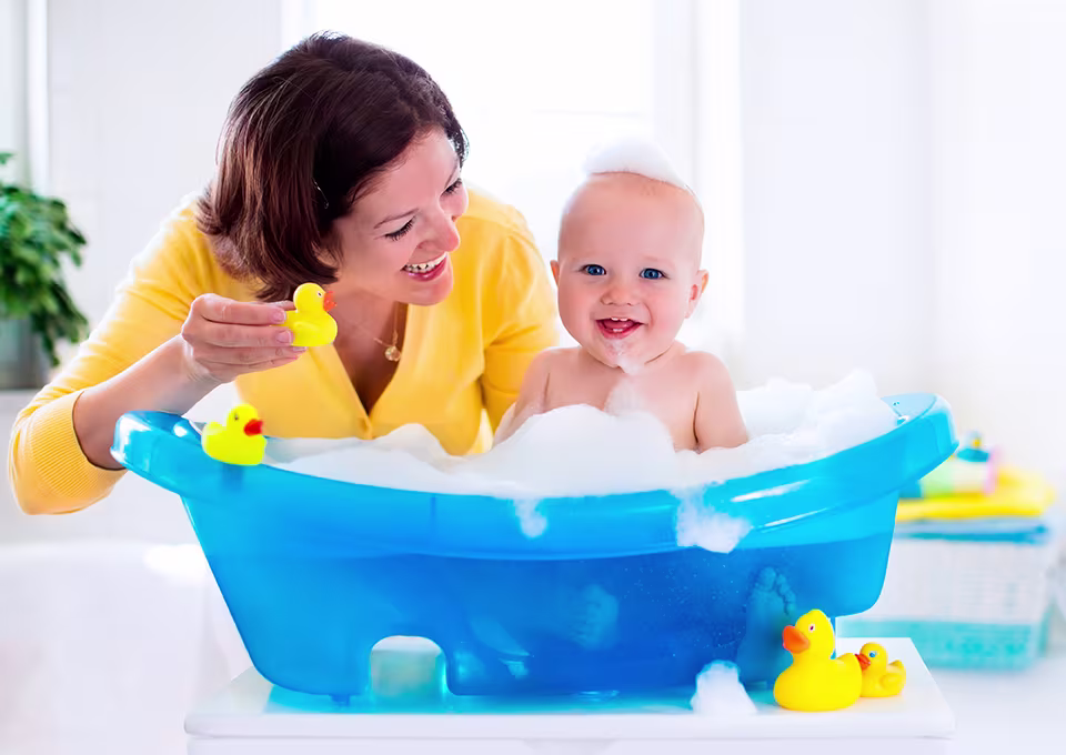 Mamá bañando a su pequeño en tina de baño para bebé.
