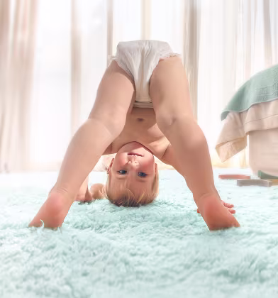 En baby som har på seg en bleiebukse ser opp og ned