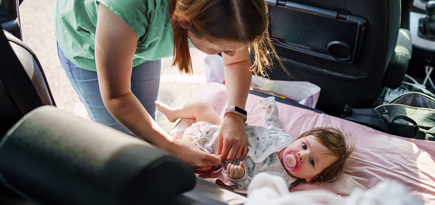 A mom is changing the diaper on the car seat.