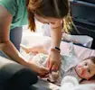 A mom is changing the diaper on the car seat.