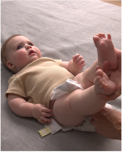 A joyful baby smiles as their parent removes their diaper, getting ready for a diaper change
