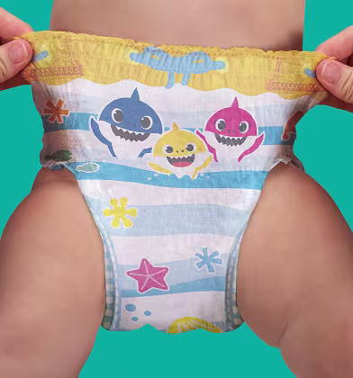 A pair of hands stretches out the sides of a Baby Shark-themed swim diaper on a baby's lower body, showcasing the elastic waistband and the full design.