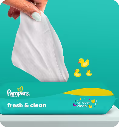 Un gros plan montre une main tirant une lingette Pampers Fresh & Clean du paquet. Un gros plan montre une main tirant une lingette Pampers Fresh & Clean du paquet.