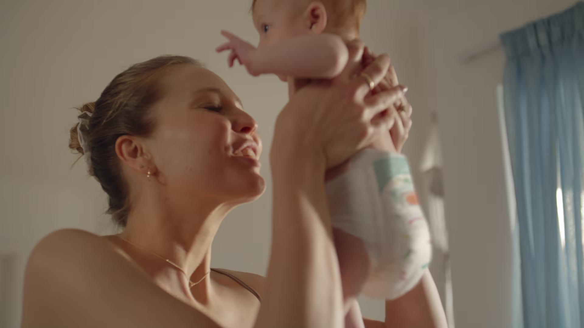 Anya újszülött gyermekét tartja, aki Pampers Premium Care pelenkát visel