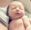 Madre limpiando la zona del cordón umbilical de un recién nacido.