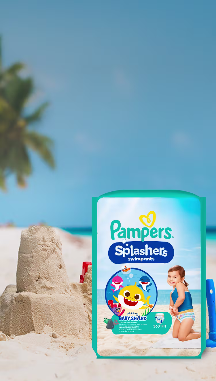 Eine Packung Pampers® Splashers Schwimmwindeln am Strand umgeben von Sandspielzeug.
