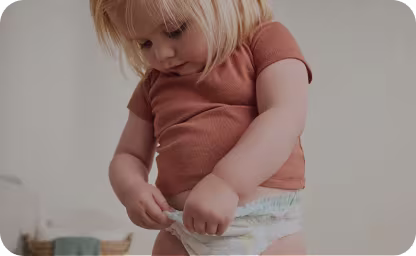 Baby looking down at diaper and pulling stretchy sides