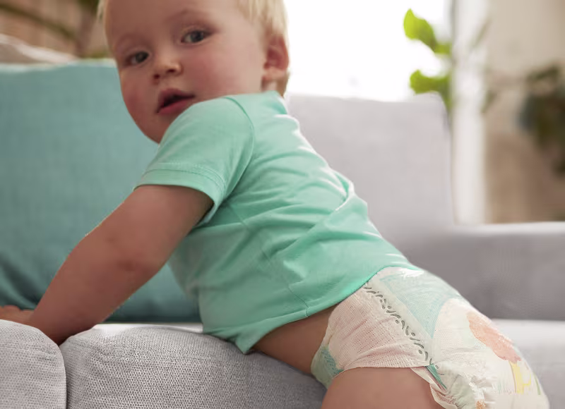 Un copil care stă în picioare în scutec Pampers Active Baby Un copil care stă în picioare în scutec Pampers Active Baby