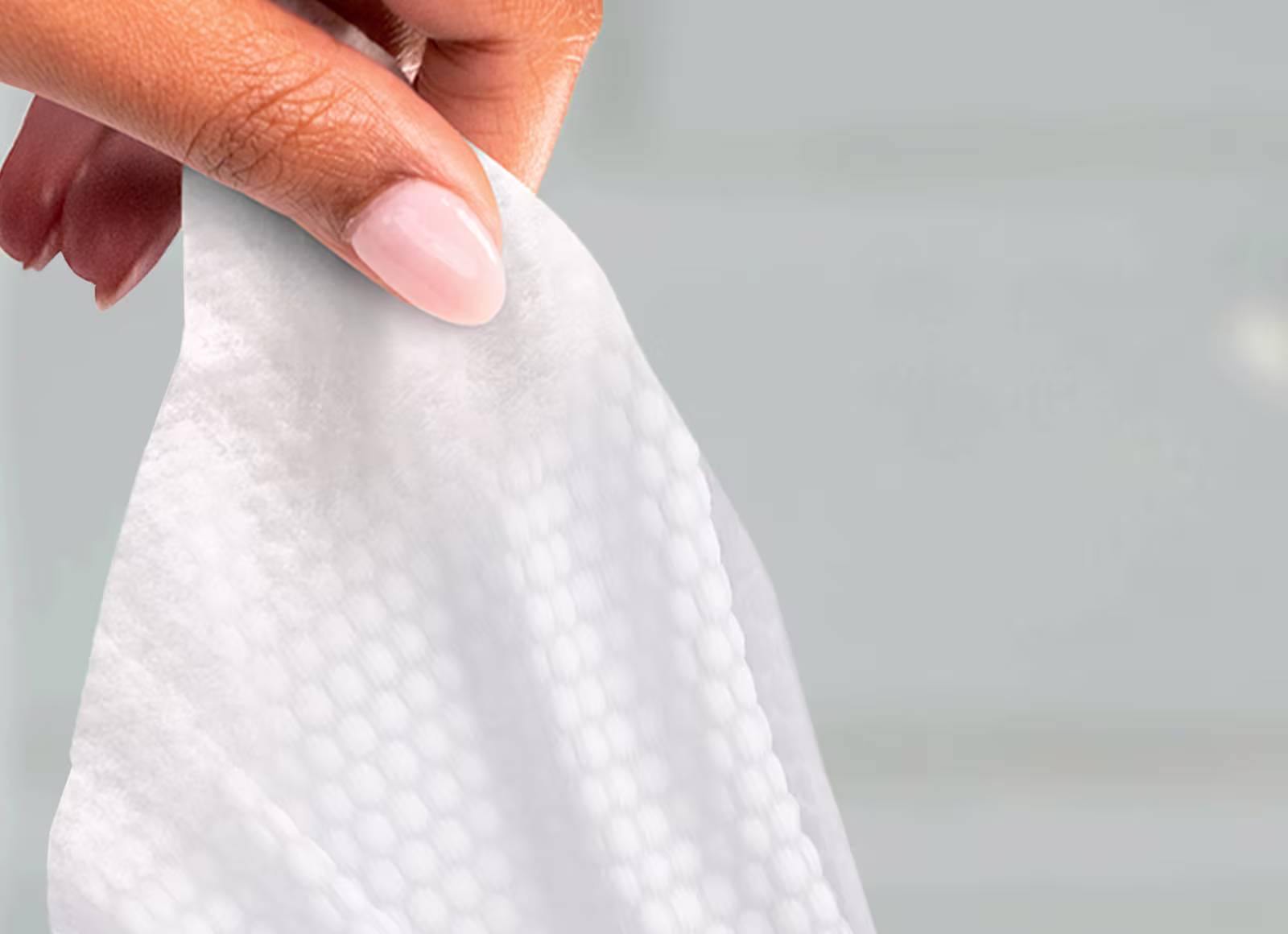 Eine Nahaufnahme eines Pampers Aqua Soft Touch Feuchttuchs, das von einer Hand einer Frau aus der Packung gezogen wird.