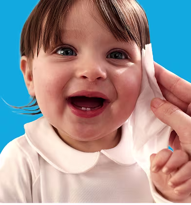 Um primeiro plano do rosto de um bebé enquanto uma mão lhe limpa suavemente a bochecha com uma toalhita Dodot. Um primeiro plano do rosto de um bebé enquanto uma mão lhe limpa suavemente a bochecha com uma toalhita Dodot.