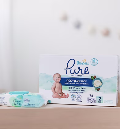 Una caja de pañales Pampers Pure sobre una mesa para cambiar pañales junto a un paquete de toallitas Pampers Aqua Pure