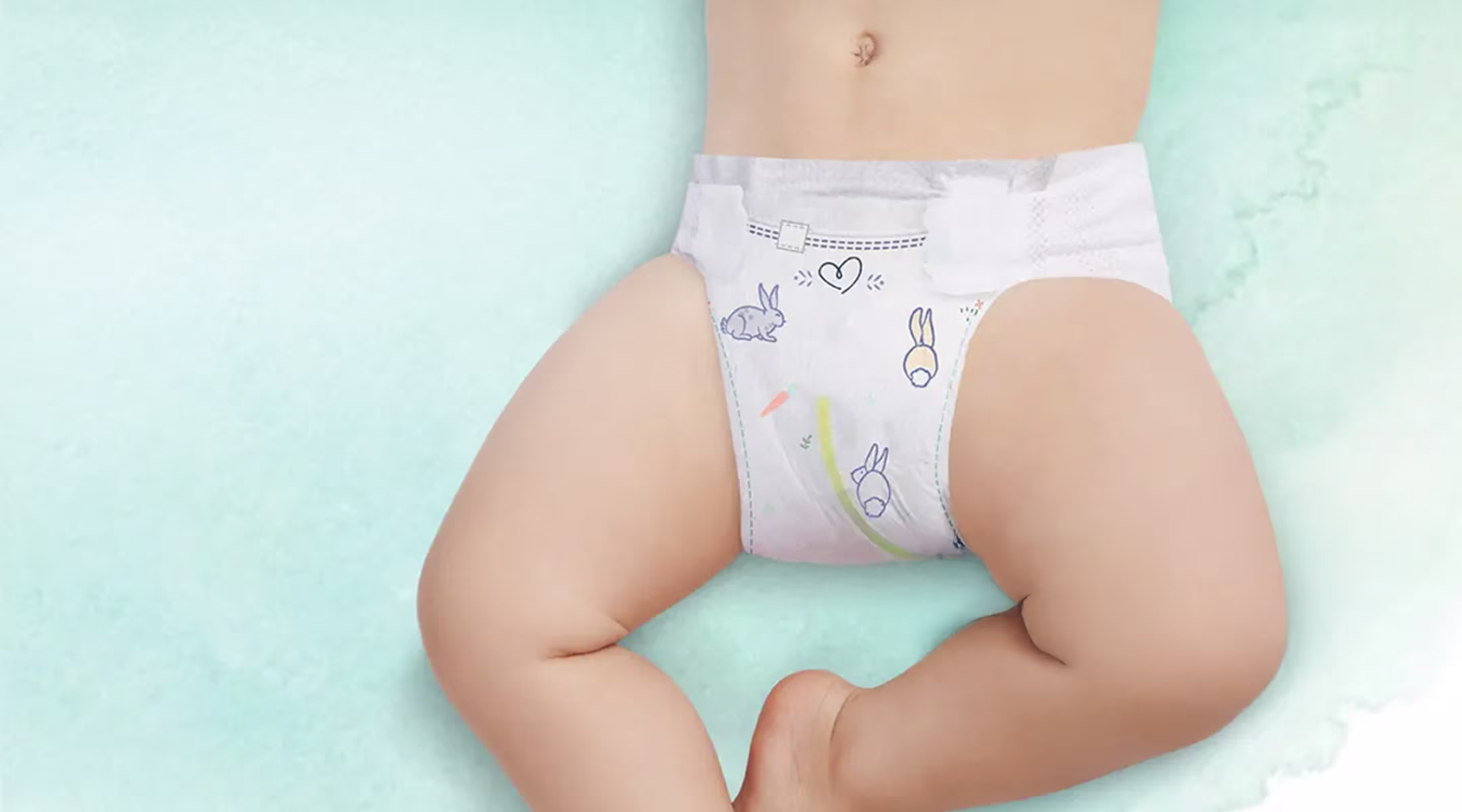 Gezicht van het bovenlichaam en de benen van een baby die Pampers Harmonie luiers draagt. Een urinindicator wordt aangeduid met een pijl.