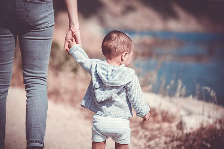 Μωρό περπατάει στην παραλία με τον γονιό του