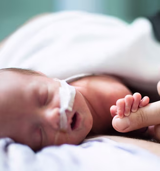 Image of a preemie baby in the NICU looking at the camera