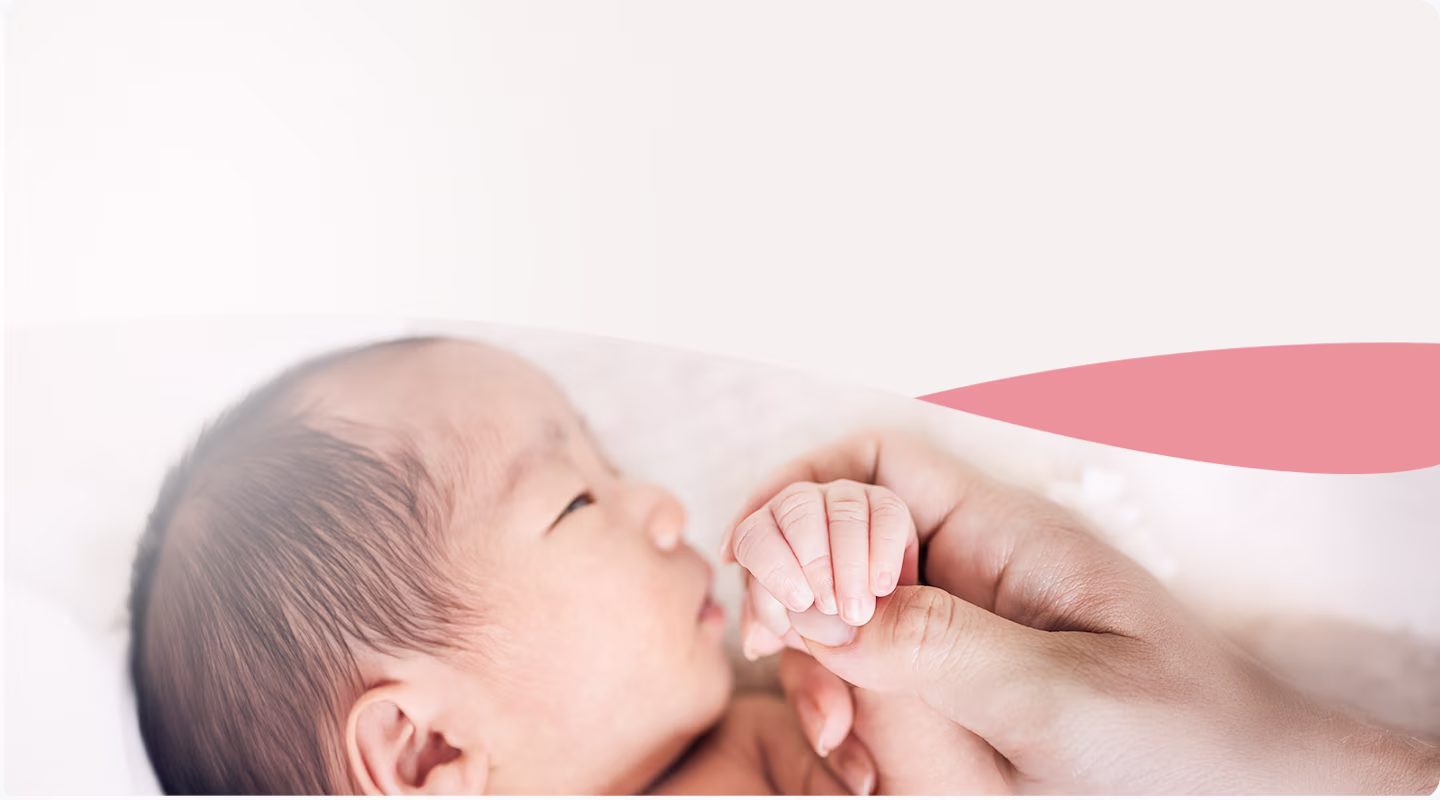 A close-up of a newborn baby holding an adult’s finger.