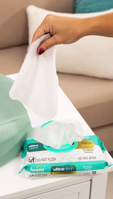 Mamá sacando una toallita ultralimpia del dispensador que está sobre una mesa para cambiar pañales